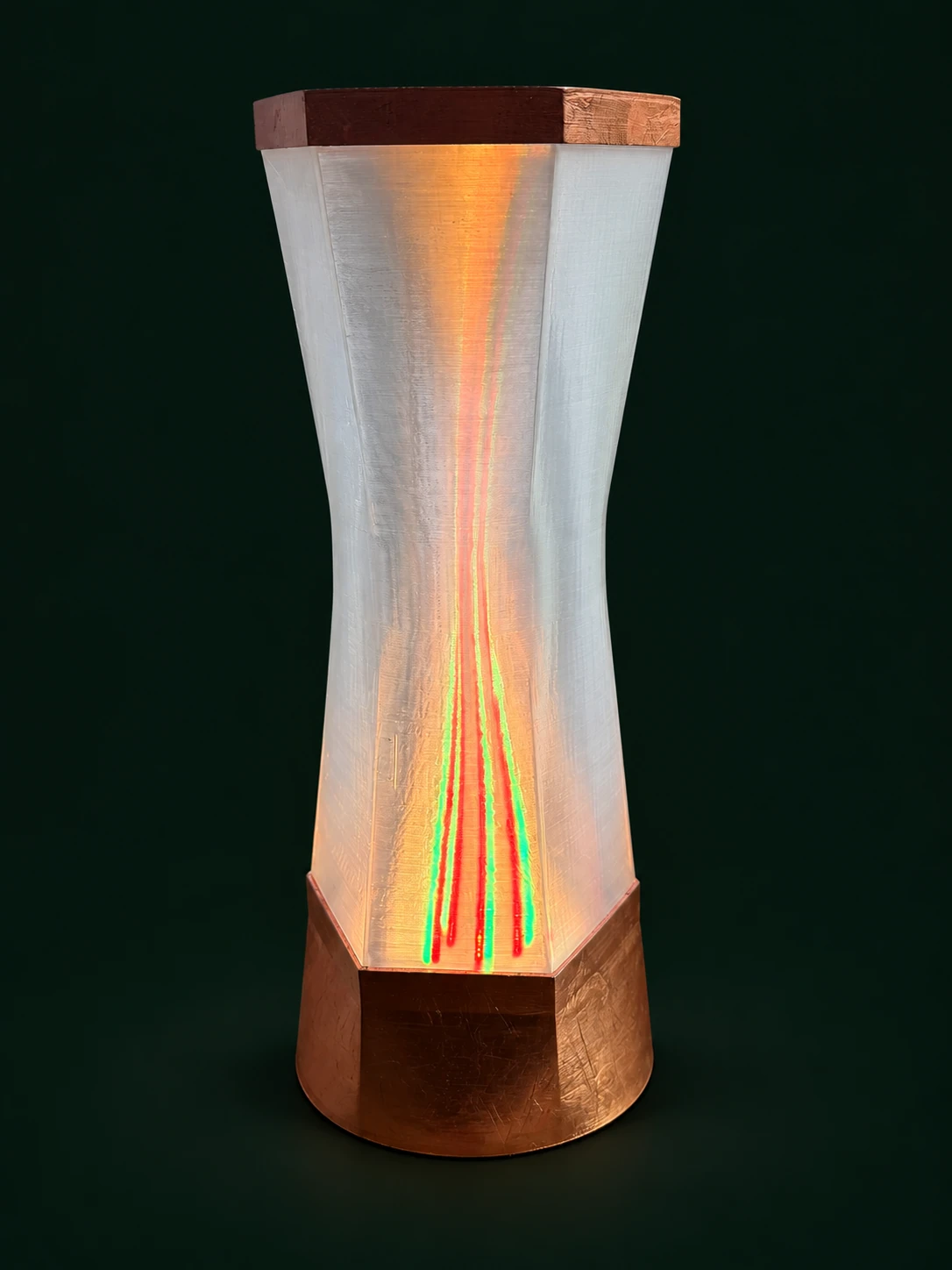 Facettierte transparente Säule auf kupferfarbenem Sockel mit roten und grünen Lichtlinien